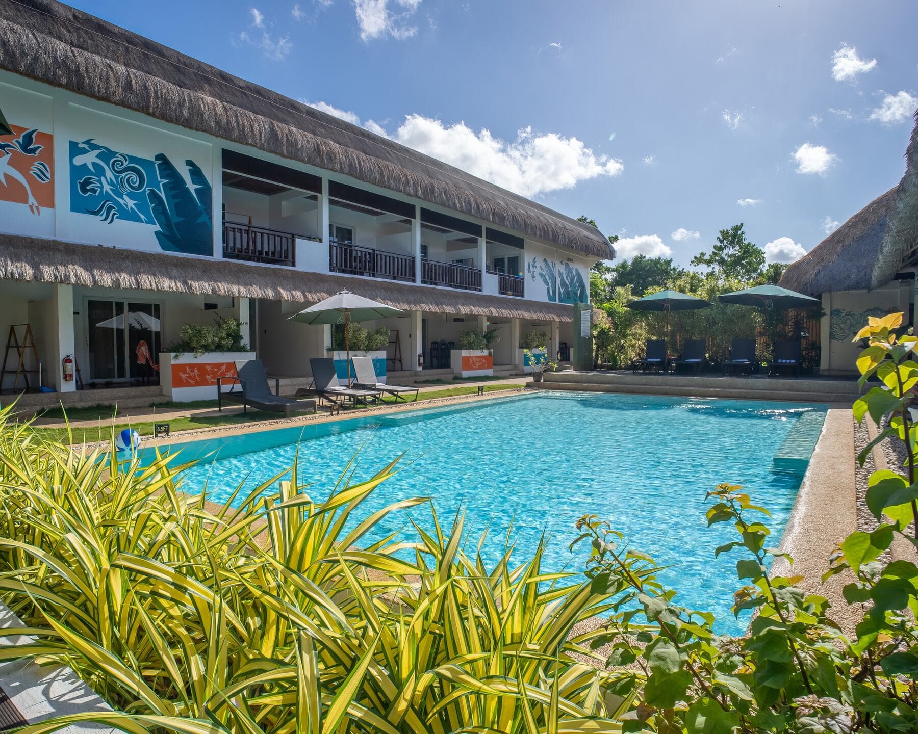 Pool and main resort building with thatched roofs