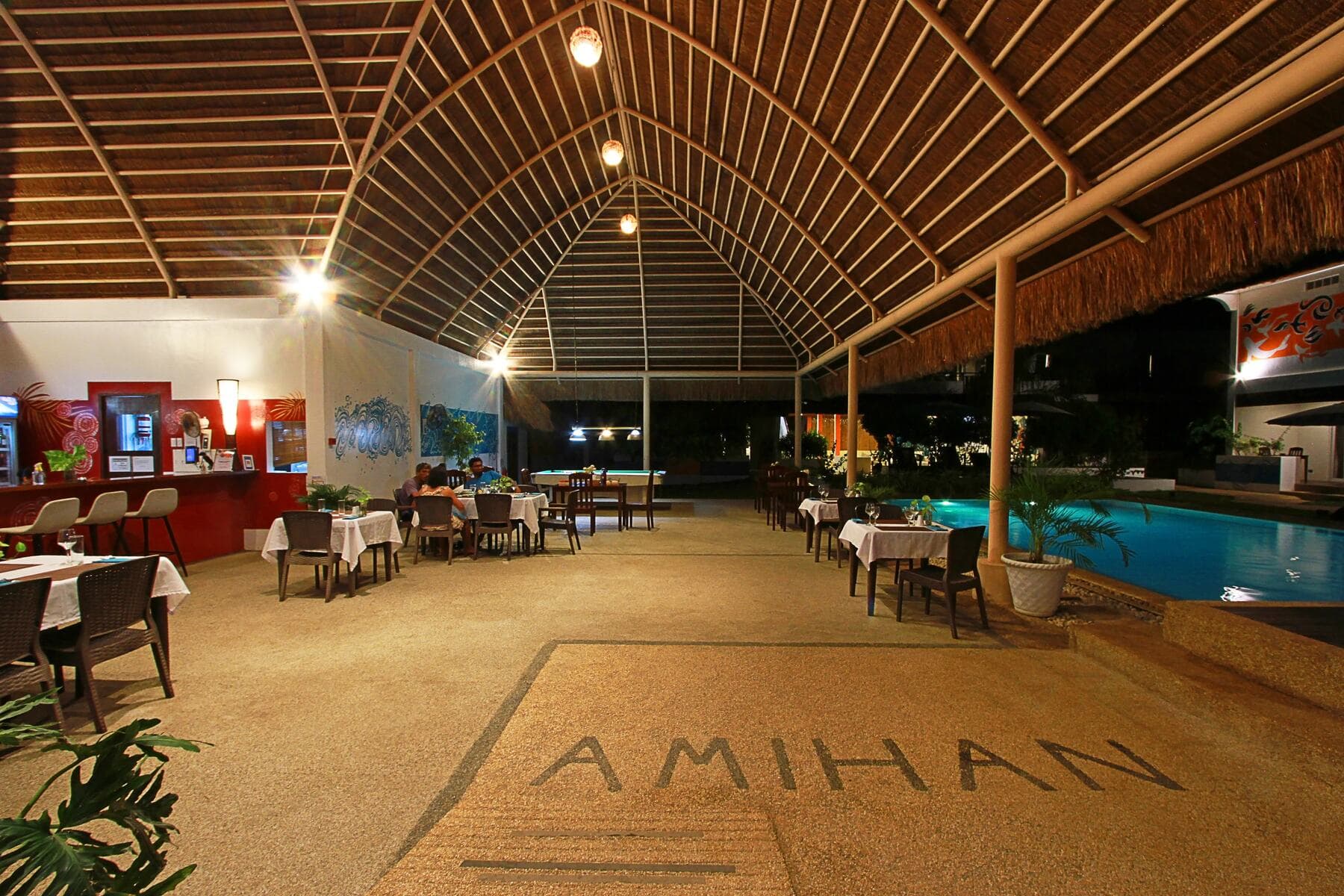 Open-air restaurant with the Amihan floor logo at night